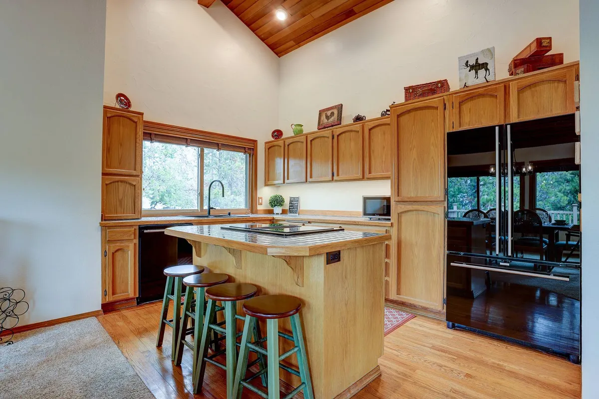 A modern kitchen with a generous island, wooden cabinets, and a large window welcomes you to cook, entertain, and gather. The setup encourages collaborative meal prep and effortless hosting, while the wood tones tie into the home’s overall warmth.